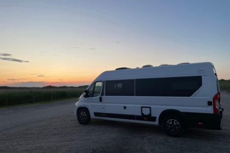 Campervan geparkt neben den Dünen, im Hintergrund der Sonnenuntergang, irgendwie kitschig aber schön